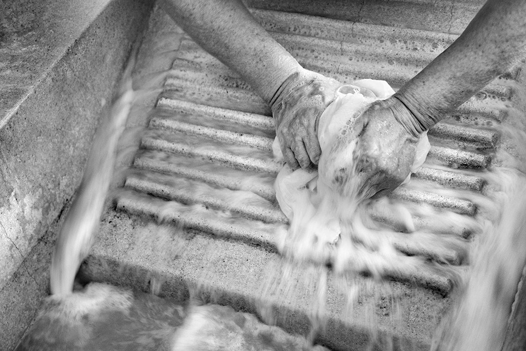 Hands washing a garment in a washbasin.